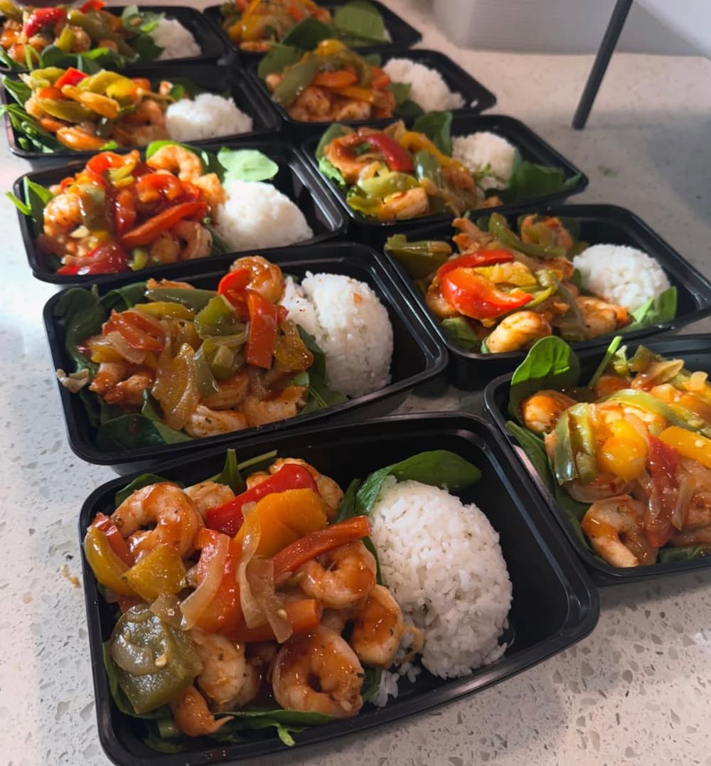 A week of meal-prep containers with shrimp, sauteed peppers and white rice